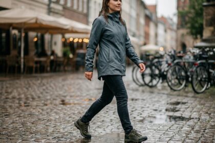 Femme portant des chaussures de marche imperméables sur un trottoir mouillé en ville sous la pluie