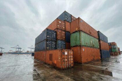 Rangée de containers maritimes empilés de 6 à 40 pieds dans un port commercial, vue grand angle au sol