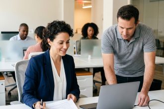 Une responsable RH et un technicien IT configurent ensemble un ordinateur portable lors de l'onboarding d'une nouvelle employée en entreprise