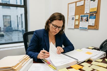 Responsable de formation stressée face aux documents d'audit Qualiopi dans un bureau administratif
