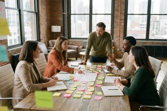 Équipe diverse réunie autour d'une table de brainstorming couverte de post-its colorés dans un bureau moderne